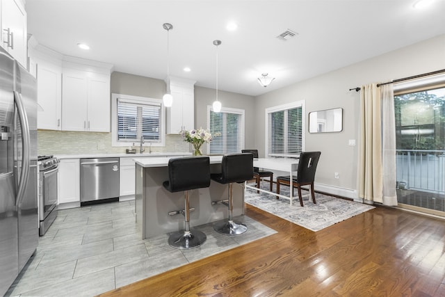 405 Commercial Ave, Cliffside Park, NJ 07010 - kitchen featuring appliances with stainless steel finishes, light countertops, backsplash, a kitchen breakfast bar, and white cabinetry