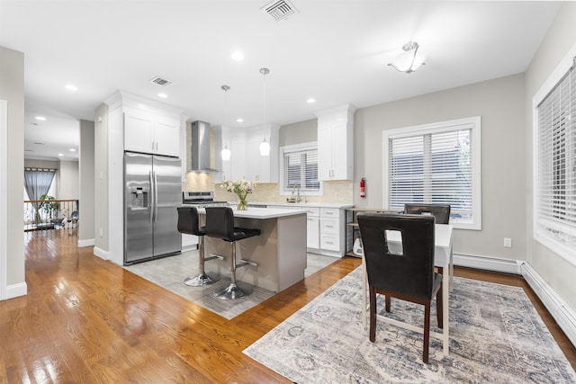 405 Commercial Ave, Cliffside Park, NJ 07010 - kitchen with appliances with stainless steel finishes, wall chimney exhaust hood, a kitchen island, decorative backsplash, and white cabinets