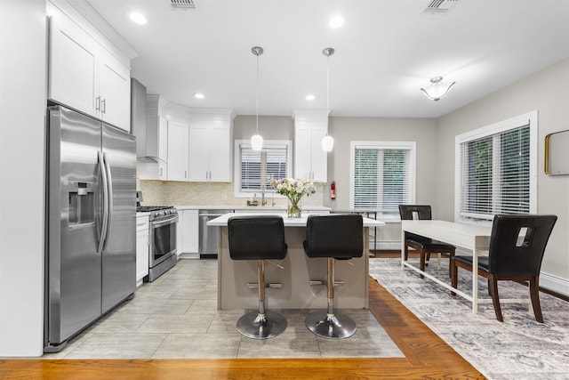 405 Commercial Ave, Cliffside Park, NJ 07010 - kitchen with appliances with stainless steel finishes, light countertops, white cabinetry, wall chimney exhaust hood, and backsplash