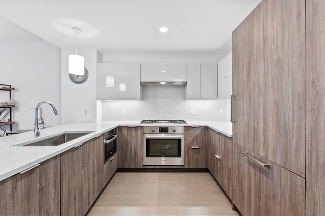 kitchen featuring stainless steel appliances, extractor fan, sink, white cabinetry, and hanging light fixtures