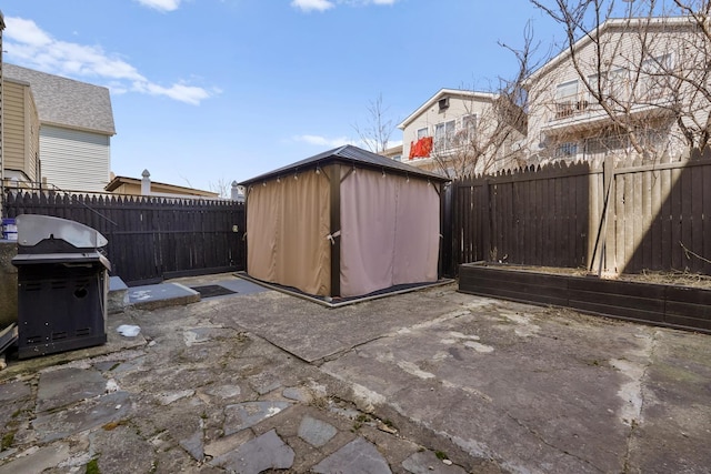 view of patio with an outbuilding, a fenced backyard, area for grilling, and a shed