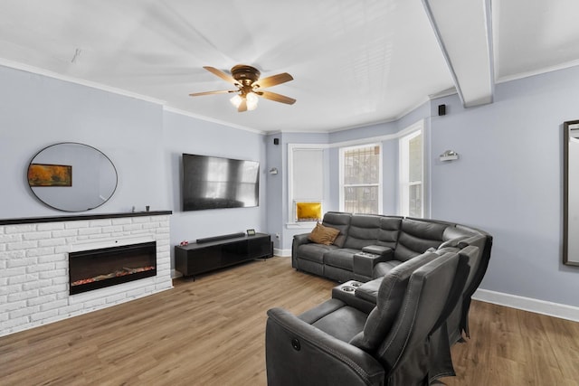 living area featuring ornamental molding, a fireplace, baseboards, and wood finished floors