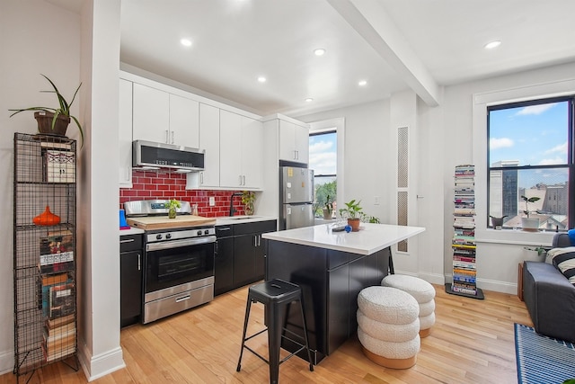 527 34th St Unit D1, Union City, NJ 07087 - kitchen featuring stainless steel appliances, light wood-type flooring, light countertops, decorative backsplash, and a breakfast bar area