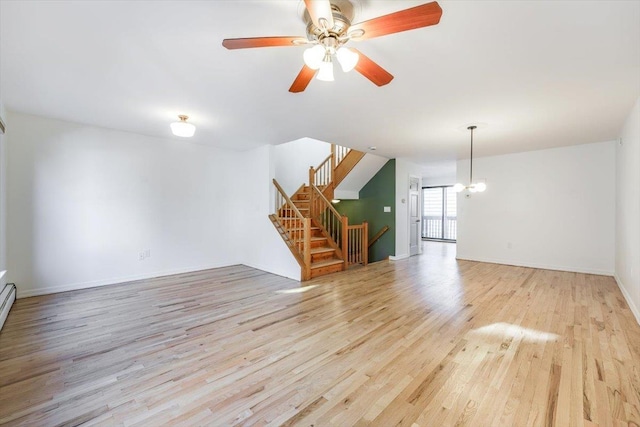 unfurnished living room featuring ceiling fan with notable chandelier and light hardwood / wood-style floors