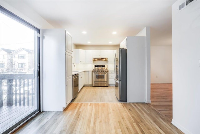 kitchen with stainless steel appliances, light wood-type flooring, and white cabinets