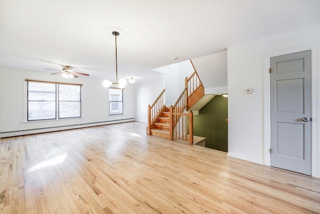 unfurnished living room with ceiling fan with notable chandelier, a baseboard radiator, and light hardwood / wood-style flooring