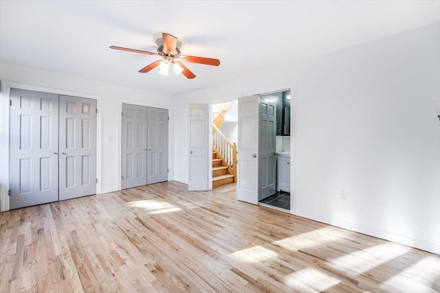 unfurnished bedroom with ensuite bathroom, two closets, ceiling fan, and light hardwood / wood-style floors