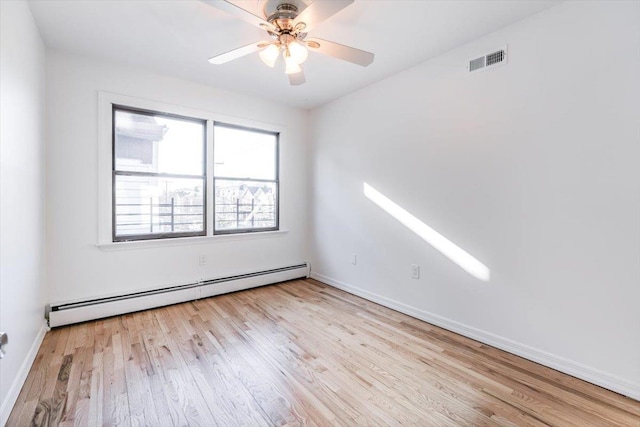 empty room featuring ceiling fan, light wood-type flooring, and a baseboard heating unit