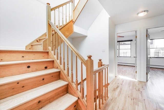 stairway featuring a baseboard heating unit and hardwood / wood-style floors