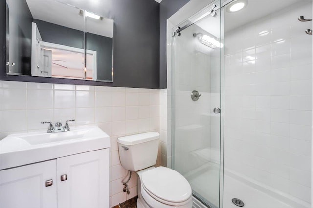 bathroom with tile walls, an enclosed shower, toilet, and vanity