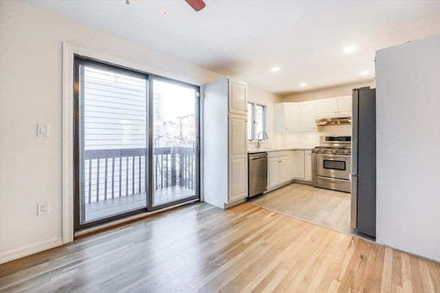 kitchen featuring light hardwood / wood-style floors, white cabinets, appliances with stainless steel finishes, ceiling fan, and sink