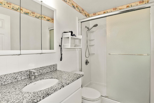 bathroom featuring vanity, toilet, a shower stall, and tasteful backsplash
