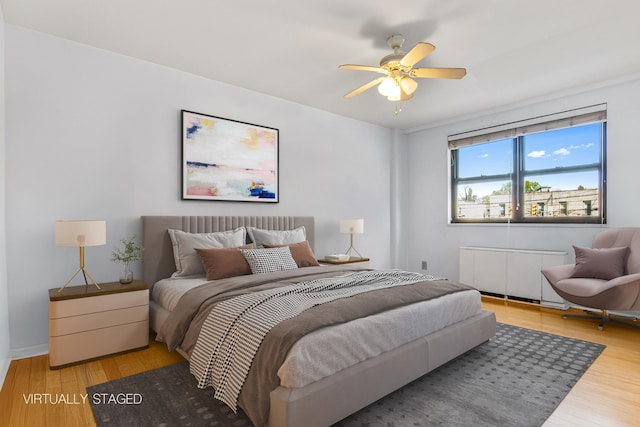 bedroom featuring a ceiling fan, radiator, and light wood finished floors