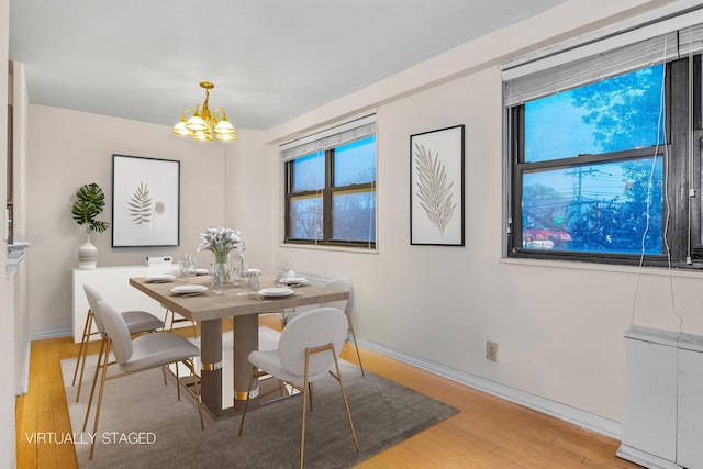 dining area with an inviting chandelier, light wood-style floors, baseboards, and a wealth of natural light