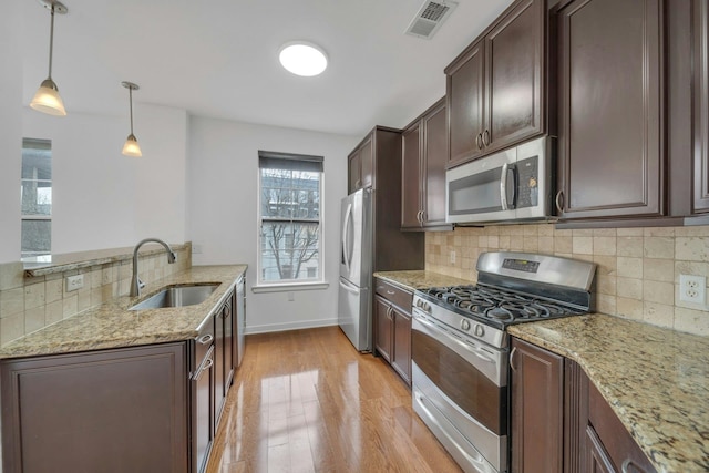 443 2nd St Unit 0212, Jersey City, NJ 07302 - kitchen with dark brown cabinets, light stone counters, a sink, light wood-style flooring, and stainless steel appliances