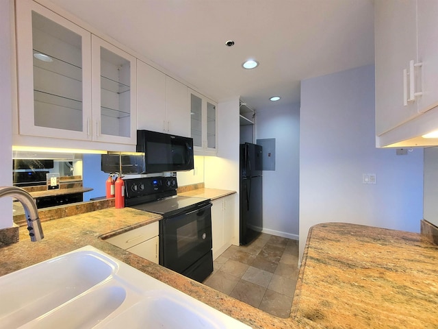 kitchen with recessed lighting, light countertops, glass insert cabinets, white cabinets, and black appliances