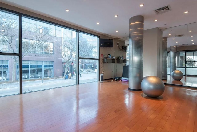 interior space with a wall of windows, recessed lighting, visible vents, and wood finished floors