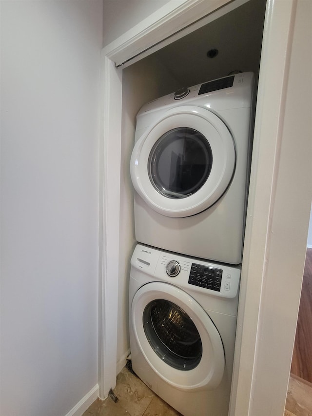 laundry area featuring baseboards, laundry area, and stacked washer / drying machine