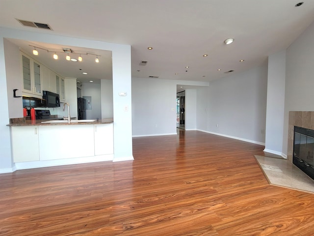 unfurnished living room with baseboards, visible vents, wood finished floors, a fireplace, and recessed lighting