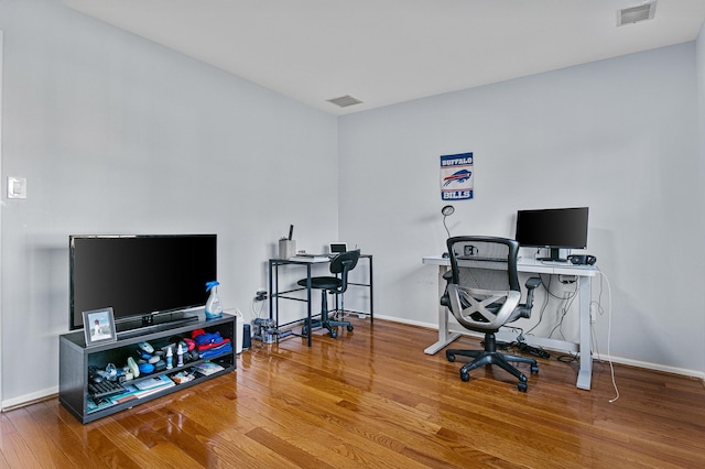 office area with baseboards, visible vents, and wood finished floors