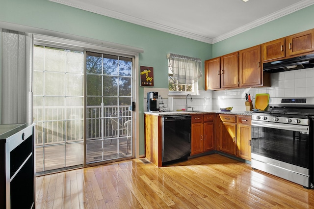 kitchen featuring brown cabinetry, a sink, stainless steel gas range, under cabinet range hood, and black dishwasher
