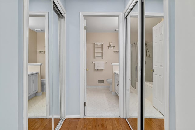 interior space with visible vents, vanity, wood finished floors, toilet, and baseboards