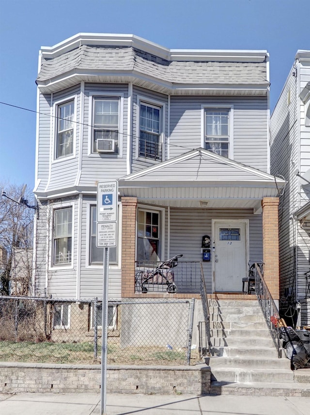 view of front of home featuring a fenced front yard, cooling unit, a porch, and brick siding