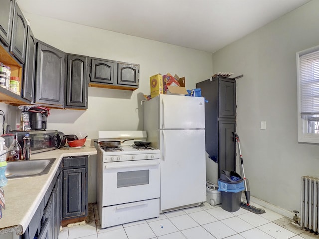 kitchen with white appliances, radiator, light tile patterned flooring, a sink, and light countertops