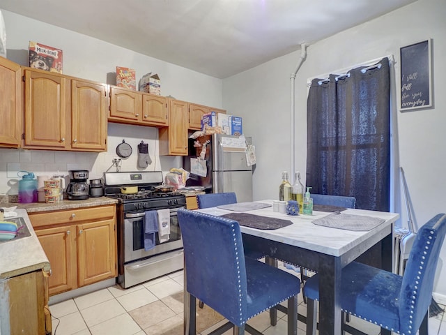 kitchen featuring light countertops, light tile patterned floors, backsplash, and stainless steel appliances