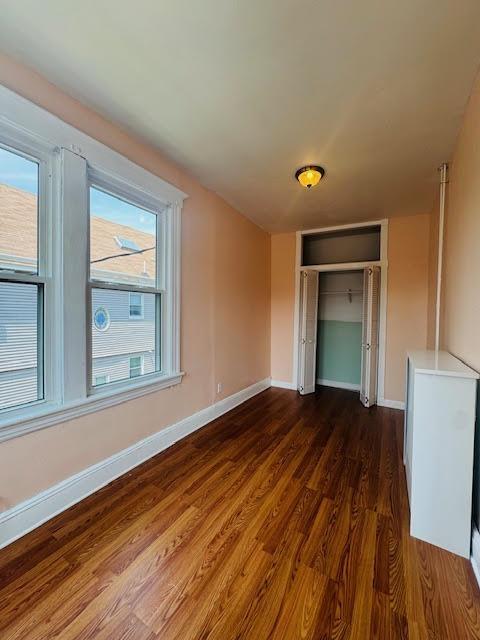 57 W 5th St, Bayonne, NJ 07002 - unfurnished bedroom featuring dark wood-style flooring, baseboards, and a closet
