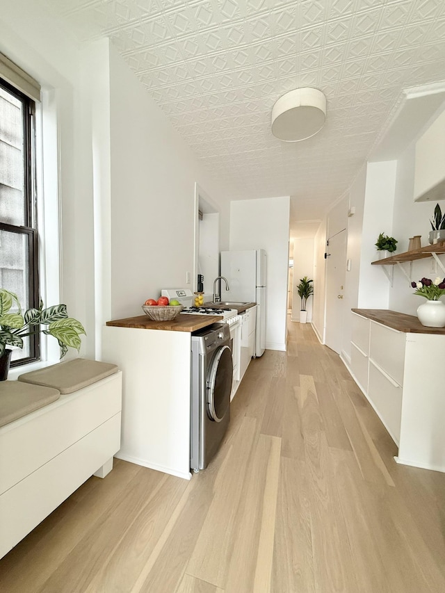 clothes washing area with laundry area, light wood-style flooring, washer / clothes dryer, and a sink