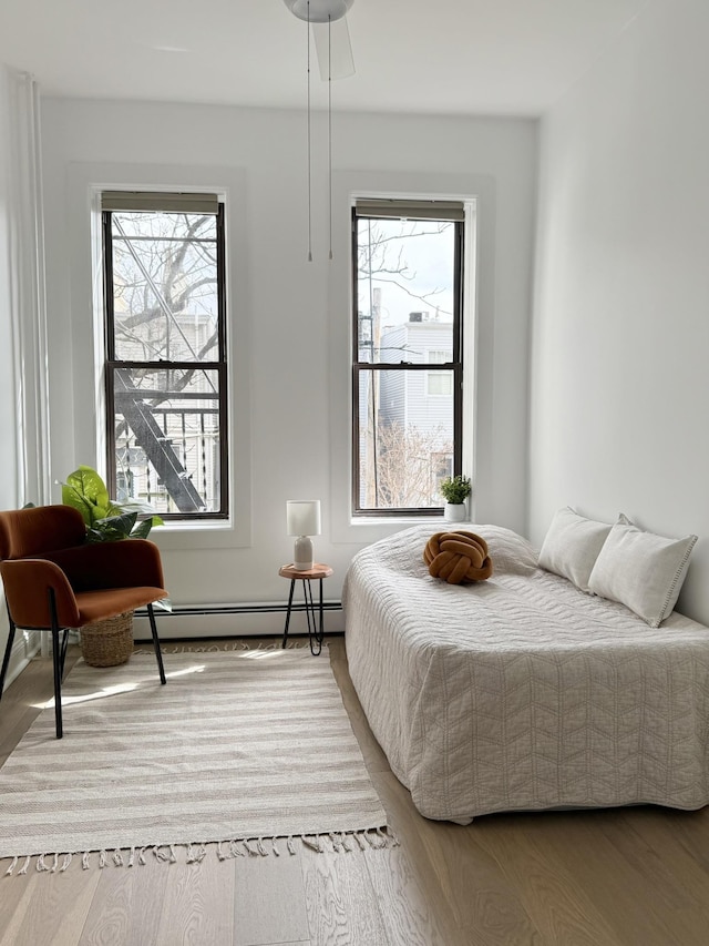 bedroom featuring a baseboard heating unit and wood finished floors