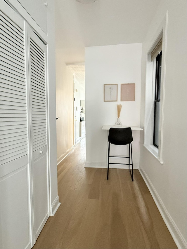 corridor with light wood-style floors and baseboards