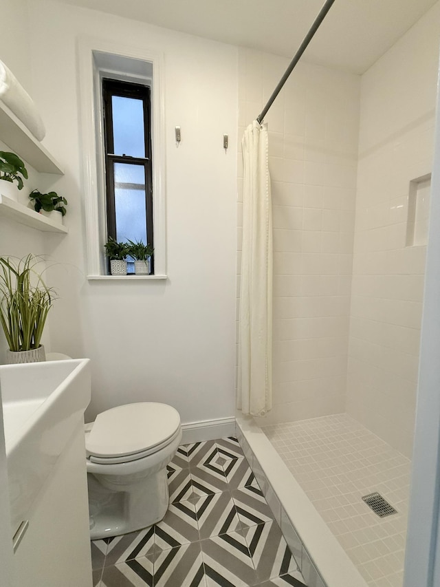 full bathroom with a stall shower, baseboards, and toilet