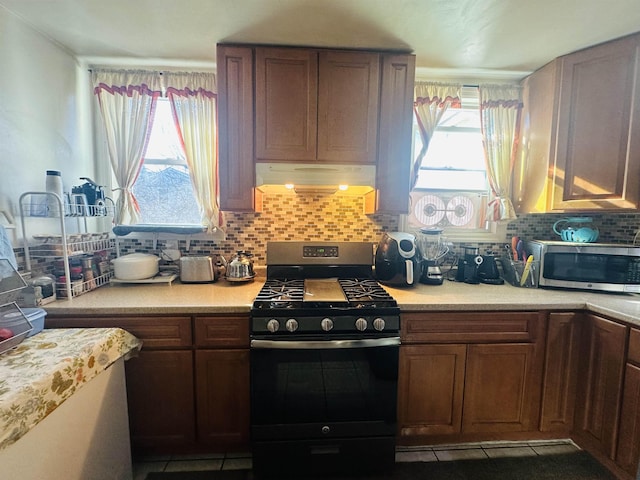 kitchen featuring light countertops, appliances with stainless steel finishes, ventilation hood, and a wealth of natural light