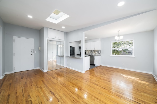 6715 Polk St Unit 12, Guttenberg, NJ 07093 - kitchen featuring appliances with stainless steel finishes, white cabinets, a chandelier, decorative backsplash, and a skylight