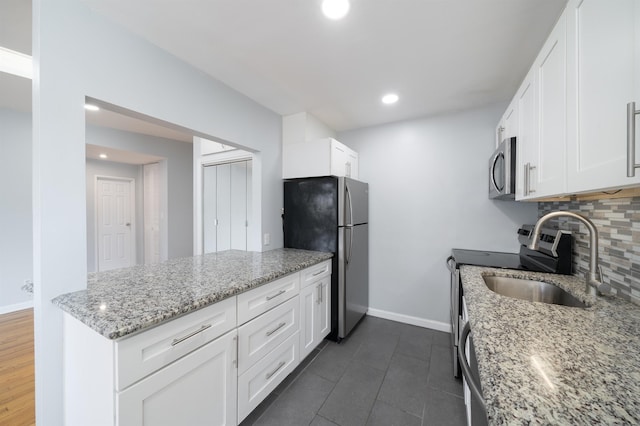6715 Polk St Unit 12, Guttenberg, NJ 07093 - kitchen with appliances with stainless steel finishes, tasteful backsplash, white cabinets, a peninsula, and light stone countertops