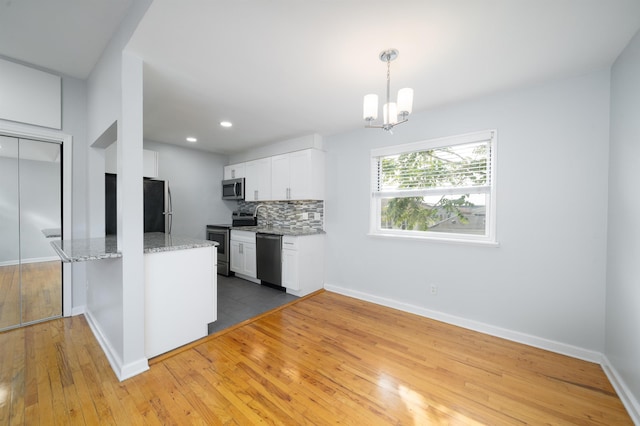 6715 Polk St Unit 12, Guttenberg, NJ 07093 - kitchen featuring appliances with stainless steel finishes, light stone counters, white cabinets, a chandelier, and backsplash