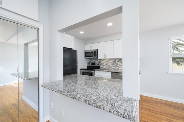 6715 Polk St Unit 12, Guttenberg, NJ 07093 - kitchen featuring stainless steel appliances, light wood-type flooring, white cabinetry, light stone counters, and backsplash