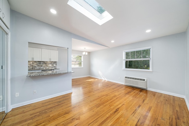 6715 Polk St Unit 12, Guttenberg, NJ 07093 - unfurnished living room featuring a wall mounted AC, light wood-style flooring, a skylight, lofted ceiling, and recessed lighting