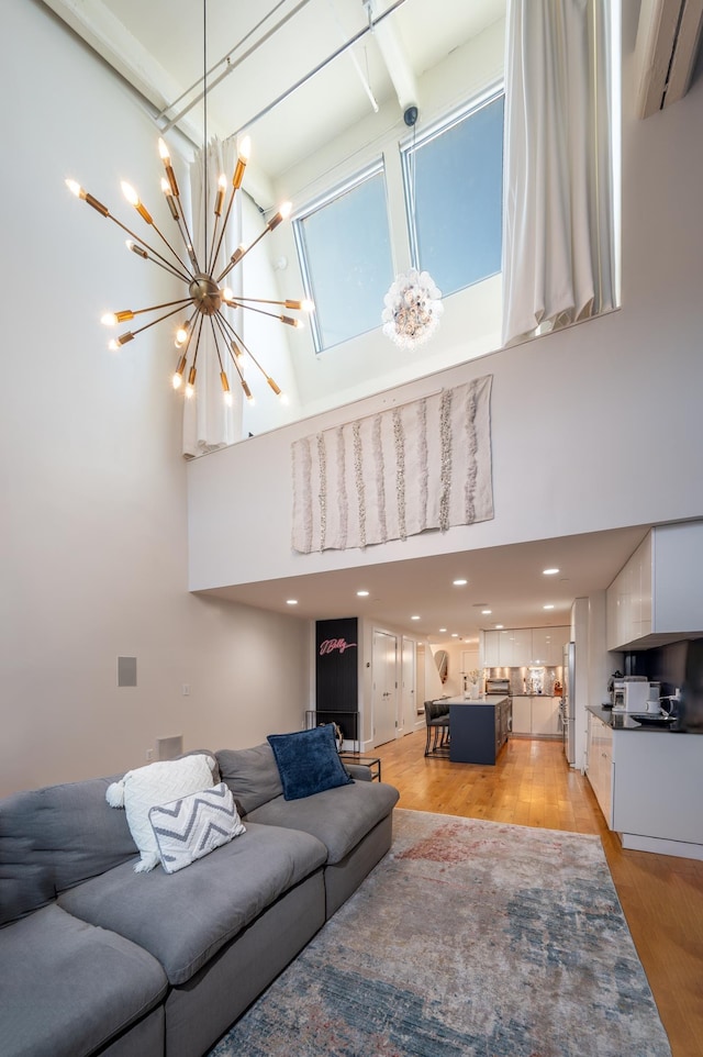 living room with a towering ceiling, light hardwood / wood-style floors, and a notable chandelier