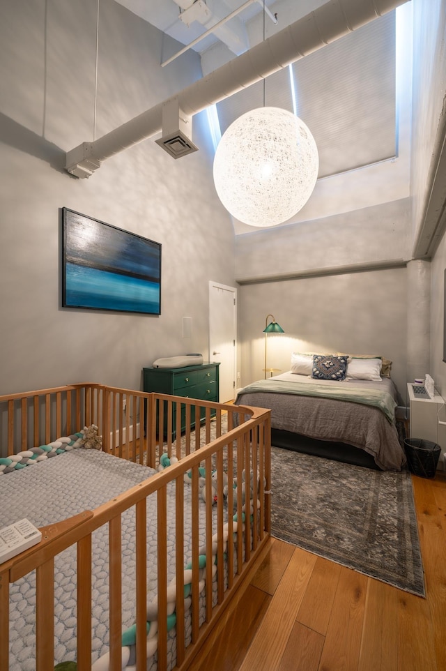 bedroom with wood-type flooring and a towering ceiling