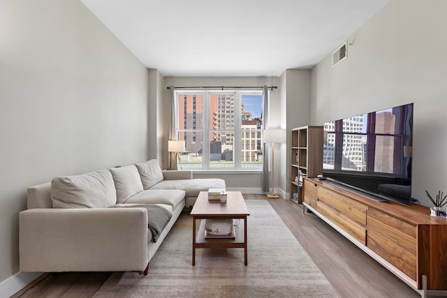 living room with wood finished floors, visible vents, and baseboards