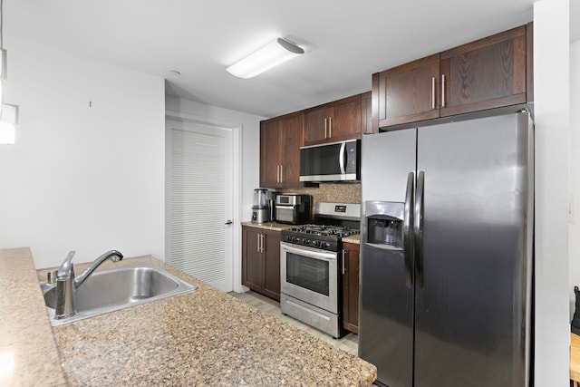 kitchen with stainless steel appliances, light countertops, a sink, and dark brown cabinetry