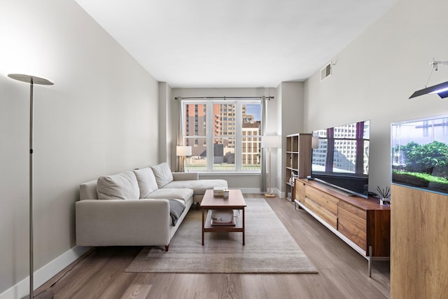 living area with visible vents, baseboards, and wood finished floors