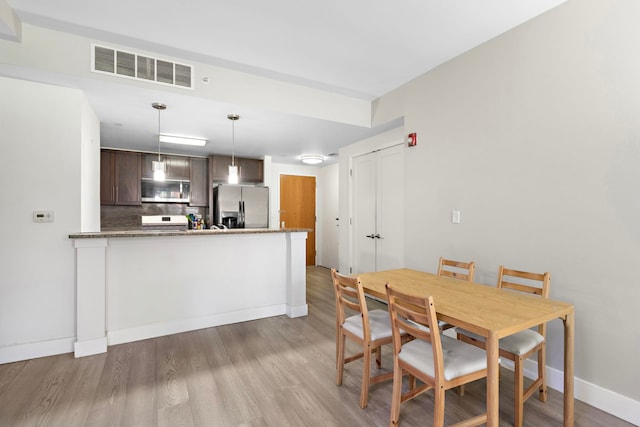 dining room with visible vents, wood finished floors, and baseboards