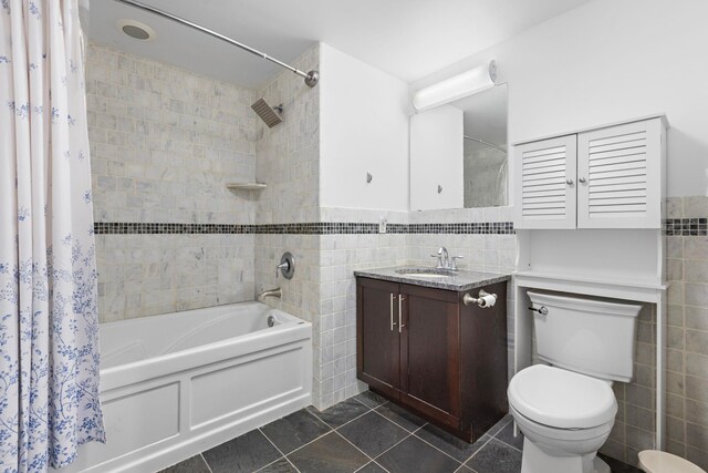 bathroom featuring tile patterned flooring, tile walls, shower / bath combo, toilet, and vanity
