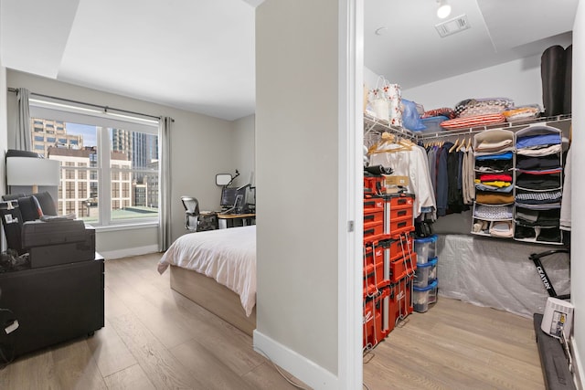 bedroom featuring a closet, visible vents, baseboards, and wood finished floors