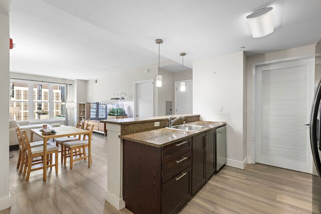 kitchen with decorative light fixtures, a sink, dark brown cabinets, light wood-type flooring, and dishwasher