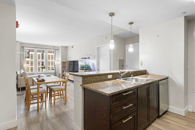 kitchen featuring a sink, open floor plan, dark brown cabinets, light wood-type flooring, and dishwasher